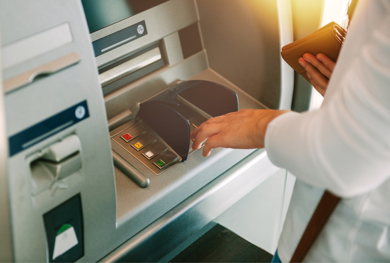 ATMs 1 - First City Payments Person utilizing an ATM while holding their wallet